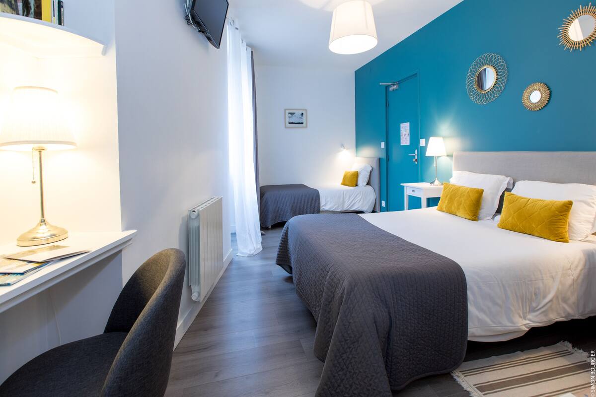 A hotel room with a large bed, a desk with a lamp, a chair, and a view of the city.