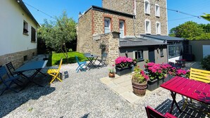 A courtyard with stone buildings, outdoor seating, and potted plants. - Hôtel Saint-Michel (Dinard)