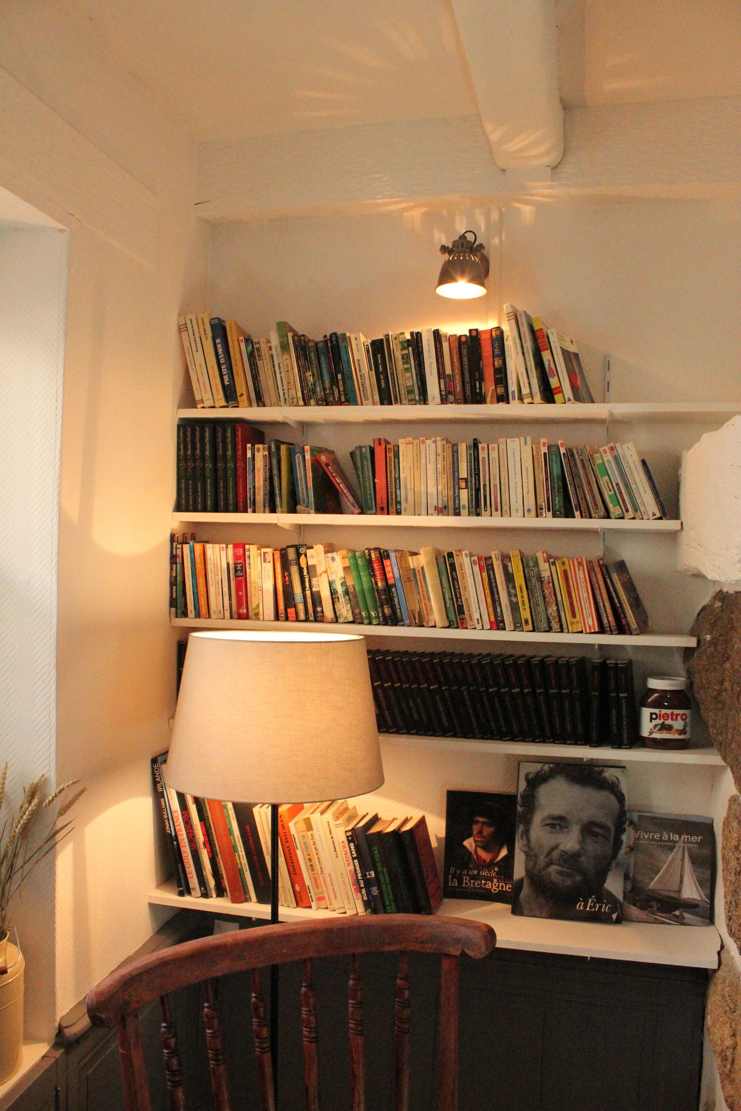 A bookshelf filled with books, a lamp, and a bottle of wine.