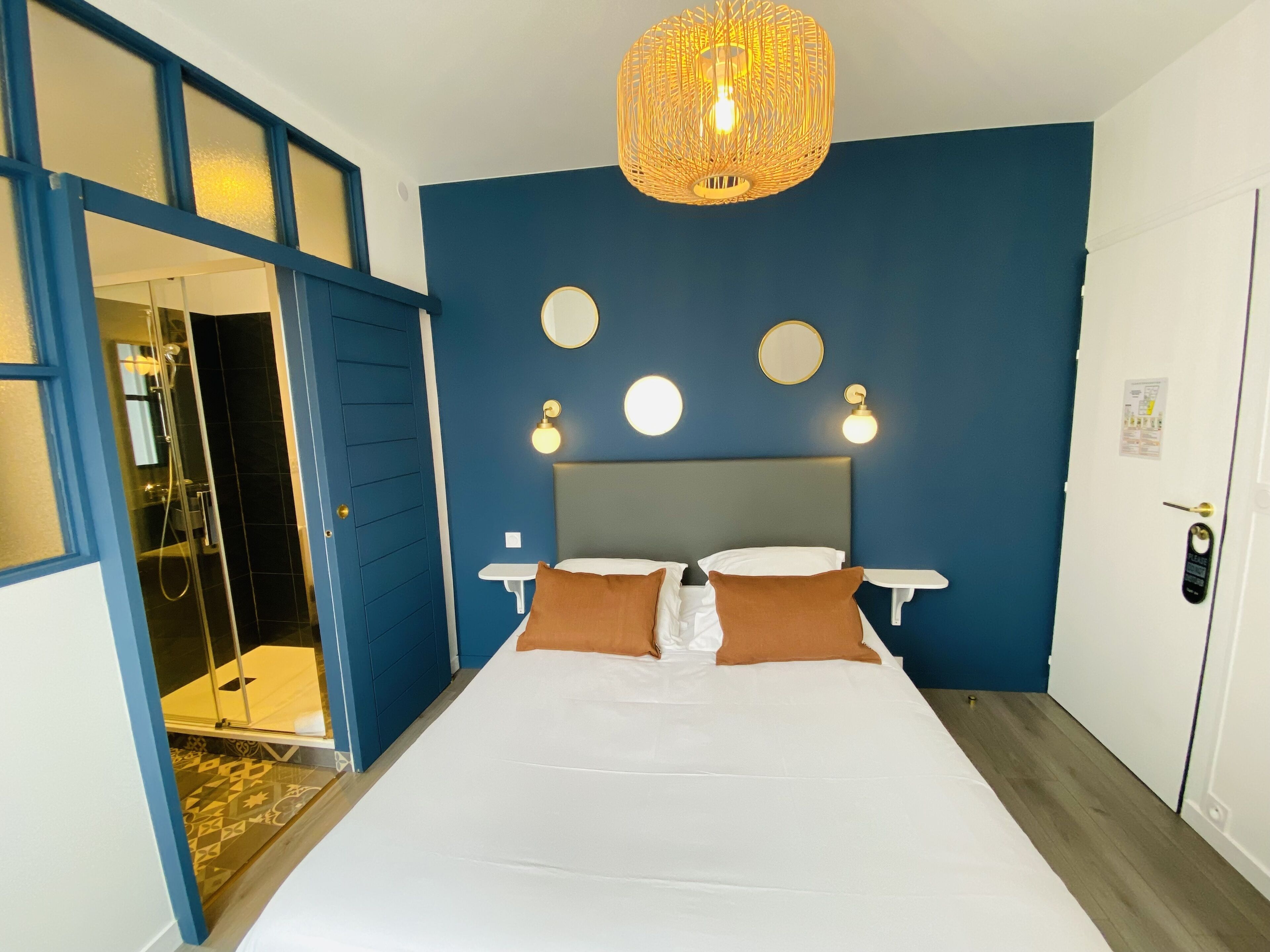 Een hotelkamer met een groot bed, een douche en een blauwe muur met drie wandlampen.