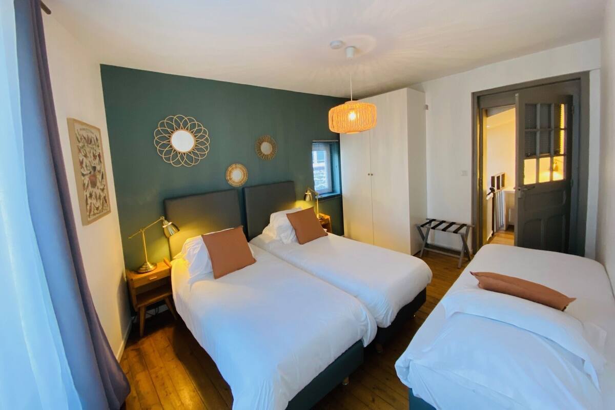 A hotel room with two beds, a large mirror, and a hanging light fixture.