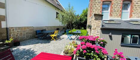 A courtyard with a red table, yellow chairs, and potted plants.