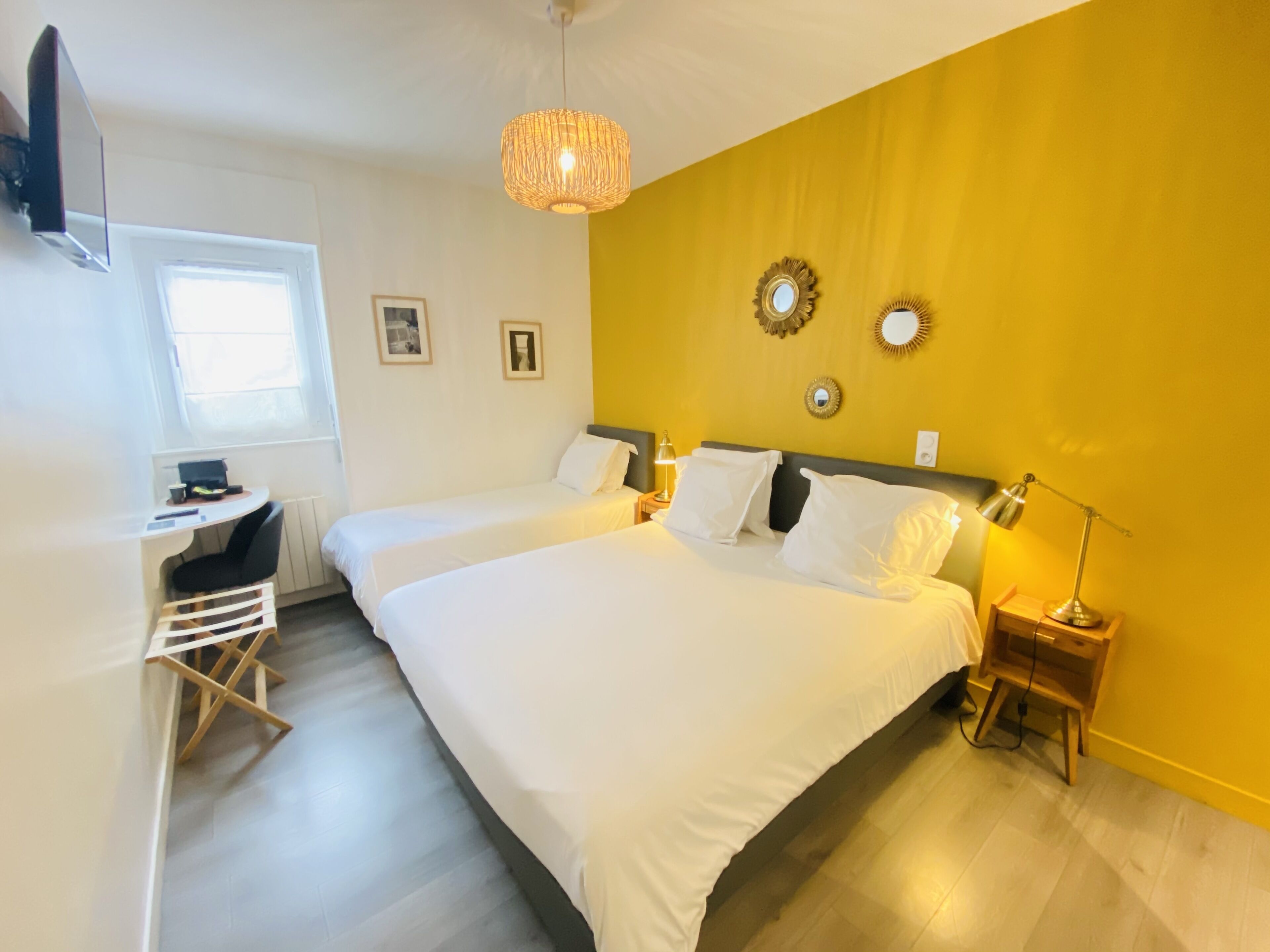 Ein Hotelzimmer mit zwei Betten, einem Schreibtisch, einem Stuhl, einem Fernseher und einem Fenster.