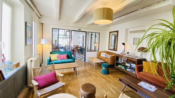 A spacious living room with a large window, a sofa, a coffee table, and a bookshelf. - Hôtel Saint-Michel (Dinard)