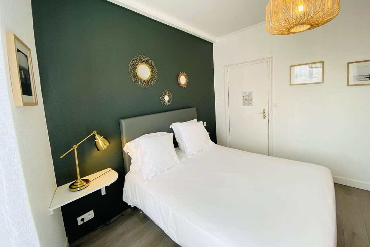 A hotel room with a bed, a bedside table with a lamp, and decorative wall mirrors.