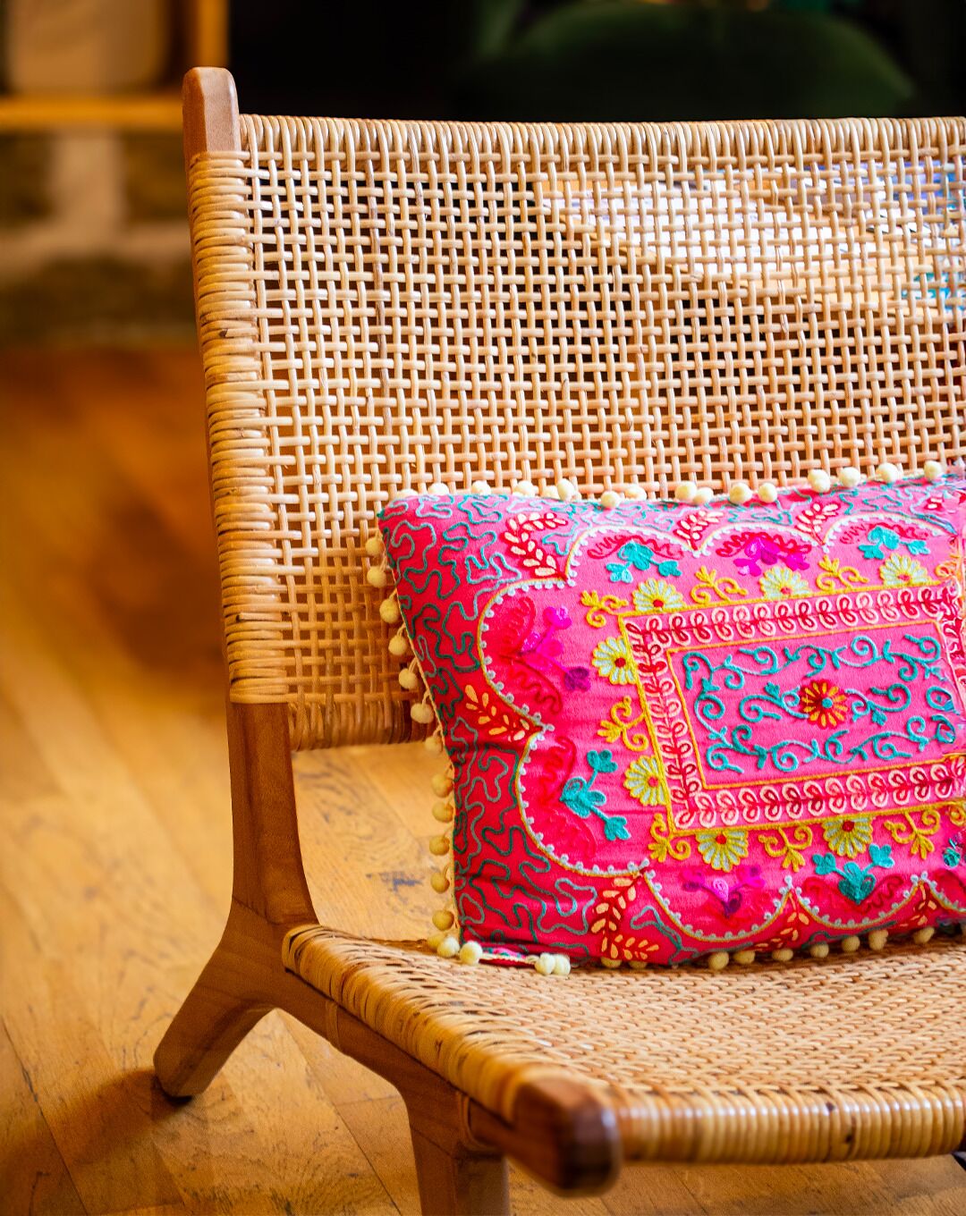 A wicker chair with a colorful cushion.