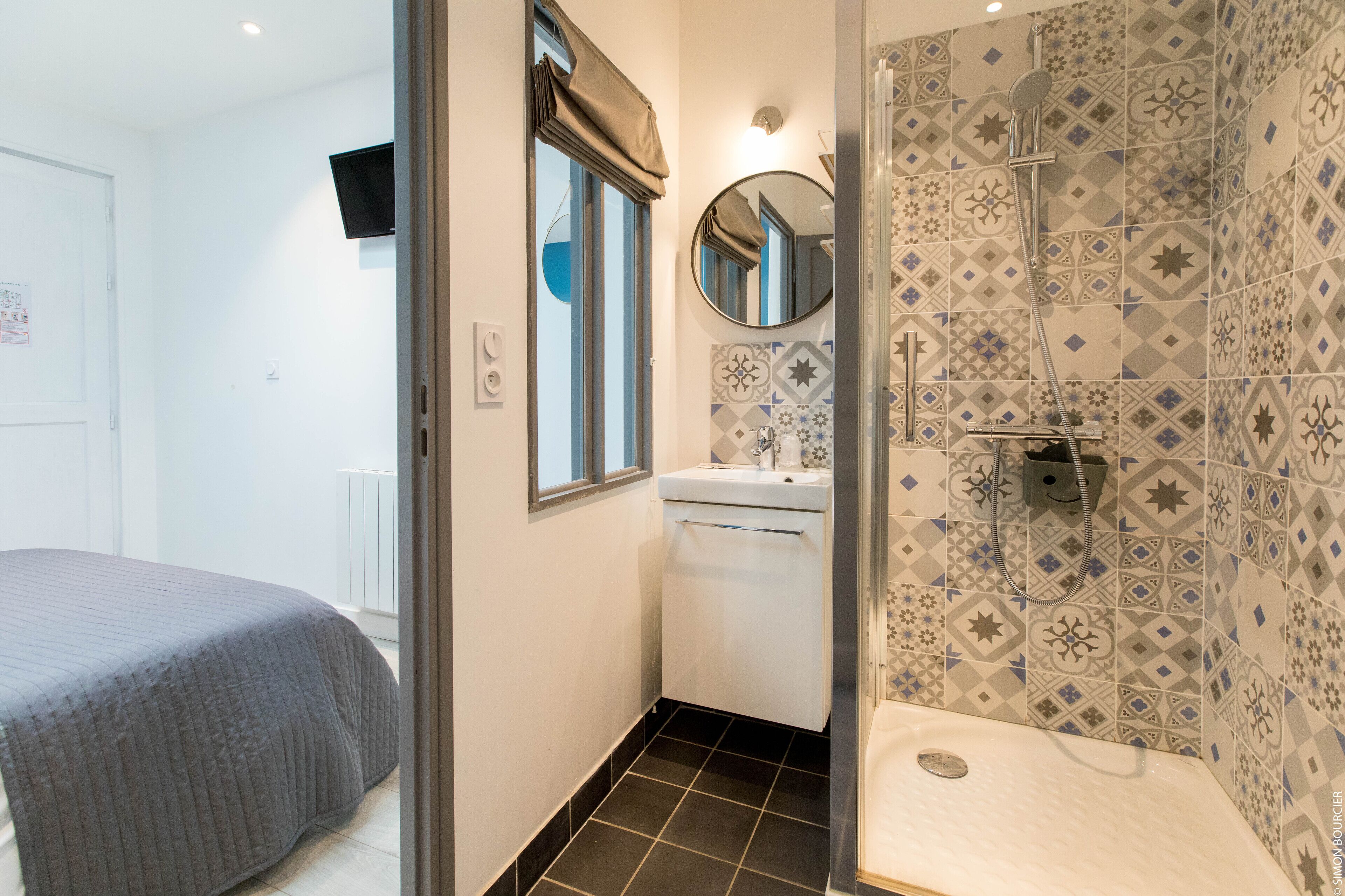 A bathroom with patterned tiles, a sink, and a shower.