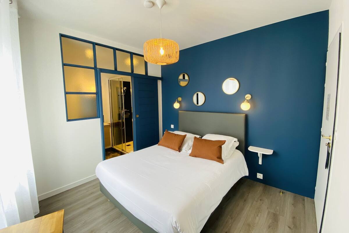 A bedroom with a large bed, a wardrobe, a shower, and a ceiling light.