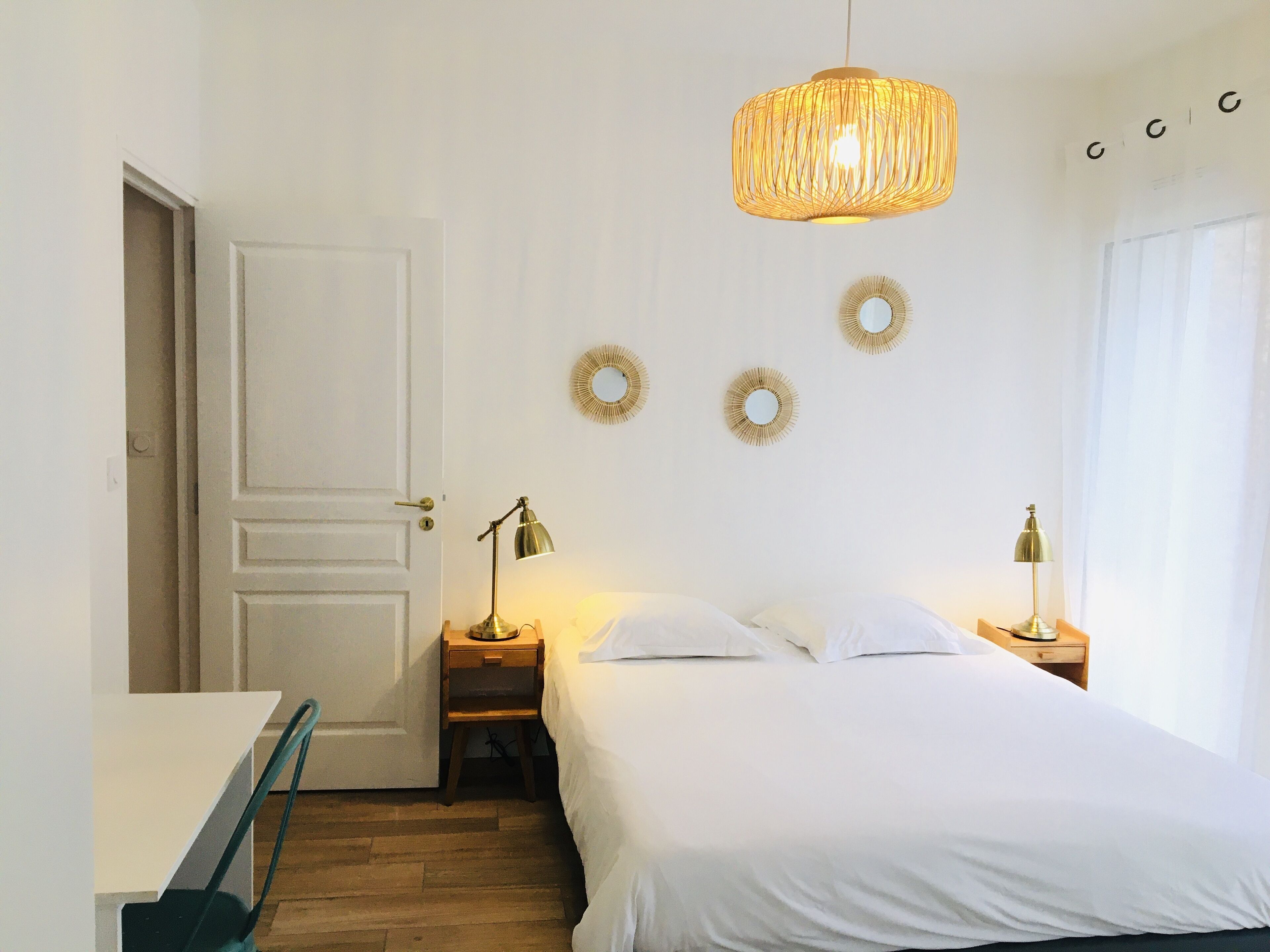 Une chambre à coucher avec un lit, des lampes de chevet, une porte et des éléments de décoration murale.