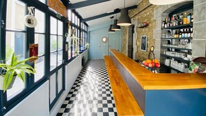 A cafe with a checkered floor, a wooden counter, and shelves stocked with bottles and glasses. - Hôtel Saint-Michel (Dinard)
