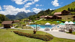 Ein Resort mit Pool, Liegestühlen und Bergblick.