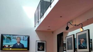 A modern interior with a bright orange sofa, a flat-screen TV, and framed pictures on the walls. - Dancenter Hotel Jomfru Ane (Aalborg)