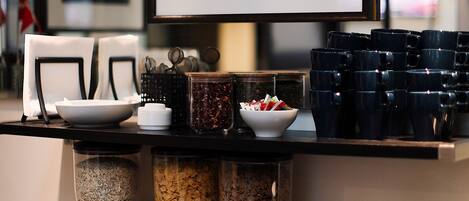 A kitchen counter with various items including a coffee machine, bowls, jars, and a framed picture.