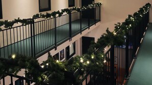 A modern interior with a balcony decorated with greenery and lights, large spherical light fixtures, and a staircase. - Dancenter Hotel Jomfru Ane (Aalborg)