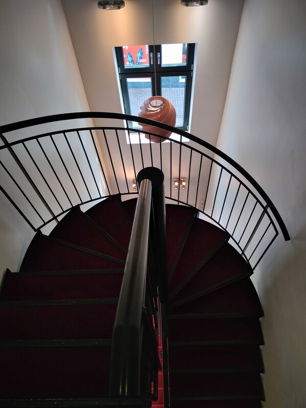A spiral staircase with a metal railing and a red carpeted landing. - Dancenter Hotel Jomfru Ane (Aalborg)
