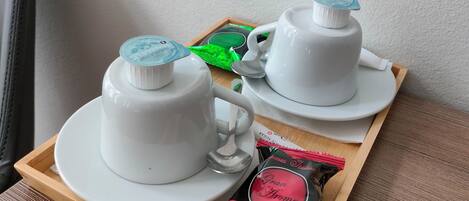 A tray with two white teapots, a green packet, and a red packet of tea bags.