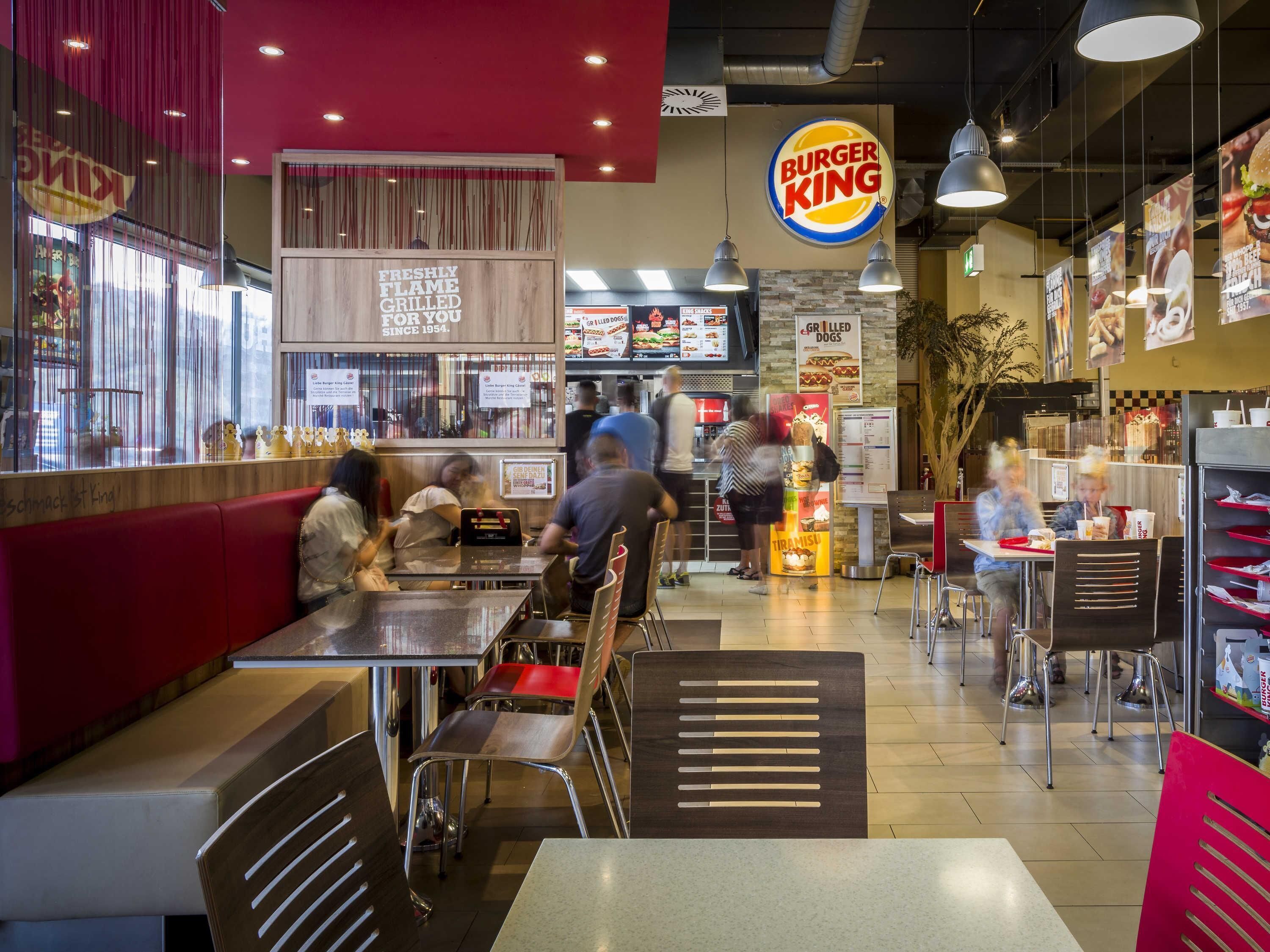 Interior de um restaurante Burger King, com mesas, balcão e painéis de menu.