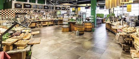 A spacious food market with various food stalls and a tiled floor.