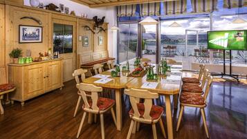 A wooden dining area with a large table, chairs, and a television.