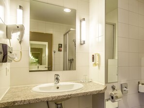 Ein Badezimmer mit Waschbecken, Spiegel, Handtrockner und Dusche.