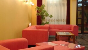 A room with a red sofa set, a glass coffee table, and a potted plant.