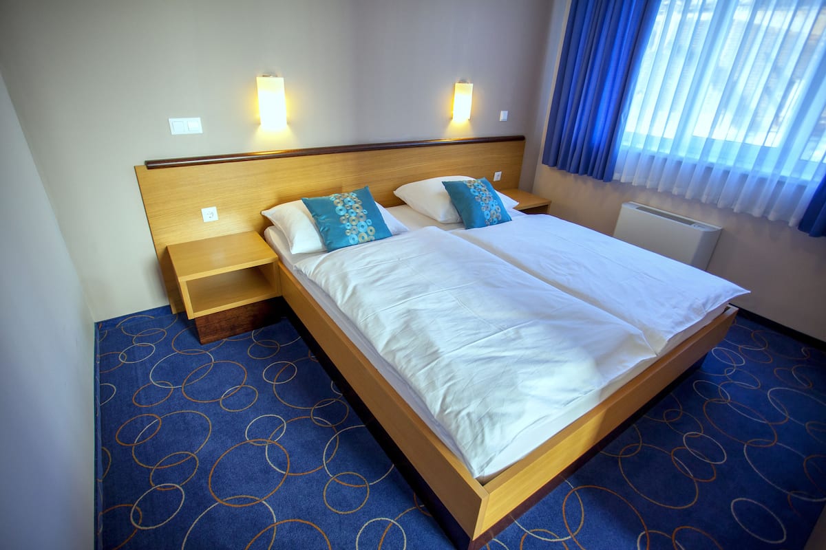 Une chambre d’hôtel avec un grand lit, deux tables de chevet et une étagère intégrée.