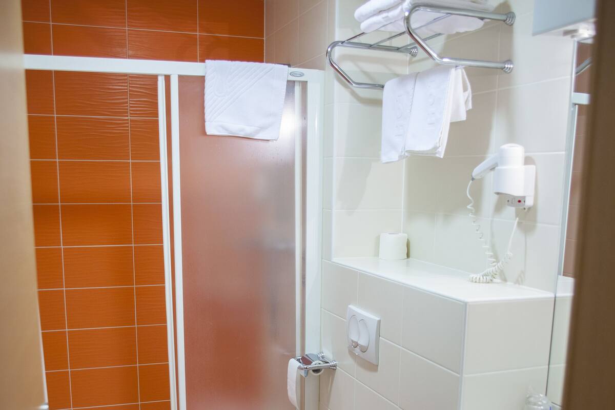 Une salle de bain équipée d’une douche, de toilettes, d’un lavabo et d’un porte-serviettes.