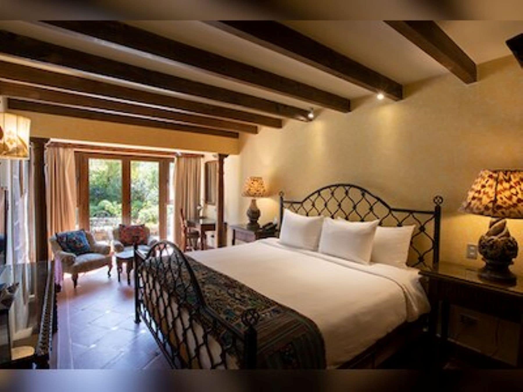 Un dormitorio con una cama grande, una silla, una mesa y una ventana.