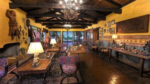 A cozy interior with wooden beams, a chandelier, and a fireplace. - Hotel Atitlán (Panajachel)