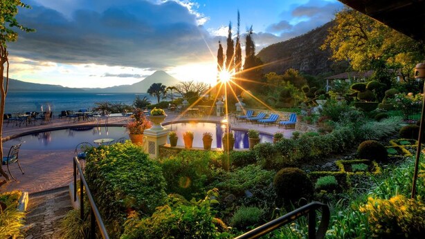 A resort with a pool, lounge chairs, and a mountainous backdrop. - Hotel Atitlán (Panajachel)