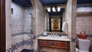 A bathroom with a shower, sink, toilet, and decorative tiles.