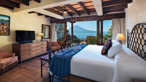 A bedroom with a large bed, a TV, a dresser, and a view of the sea. - Hotel Atitlán (Panajachel)