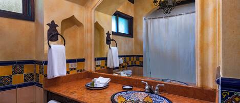 Un baño con un espejo grande, un lavabo con una pileta decorativa y un perchero para toallas.