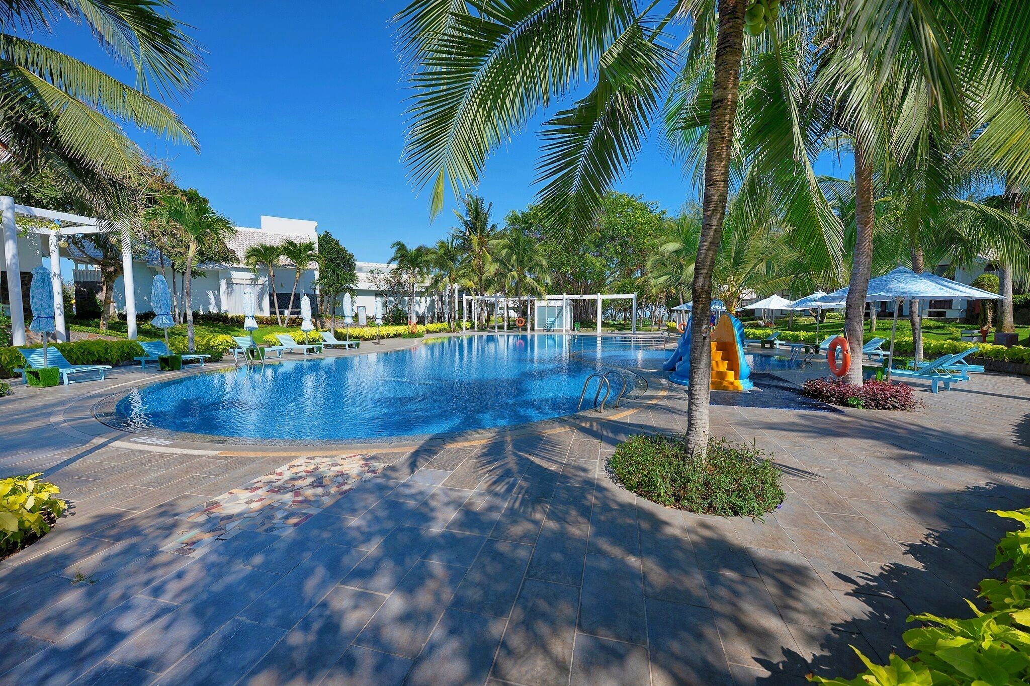 A swimming pool surrounded by palm trees and lounge chairs.