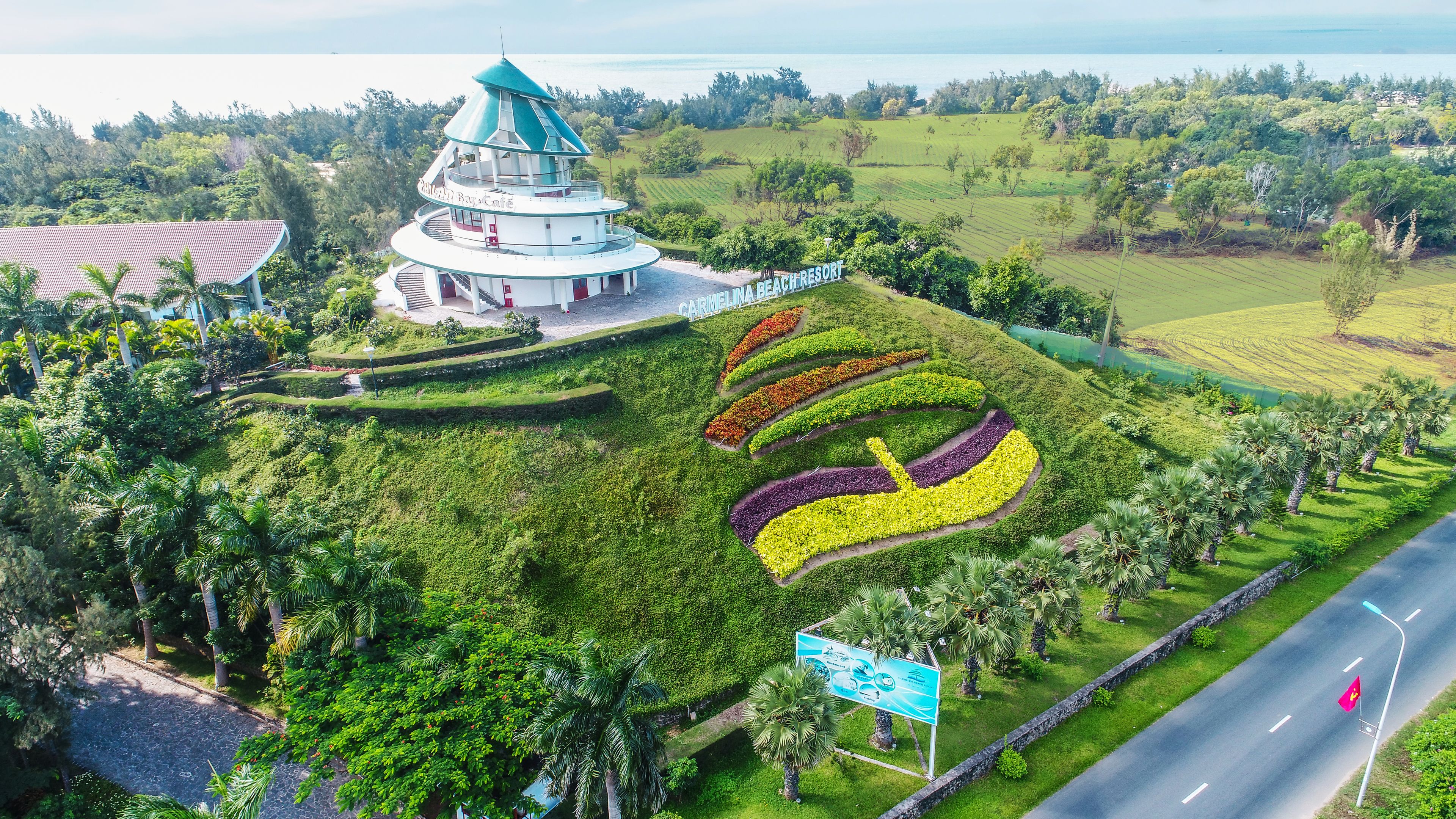 A resort with a tower, landscaped gardens, and a road.