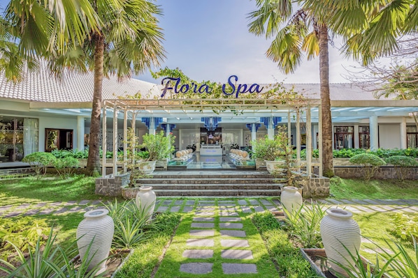 A spa with a covered entrance, stone steps, and tropical plants.
