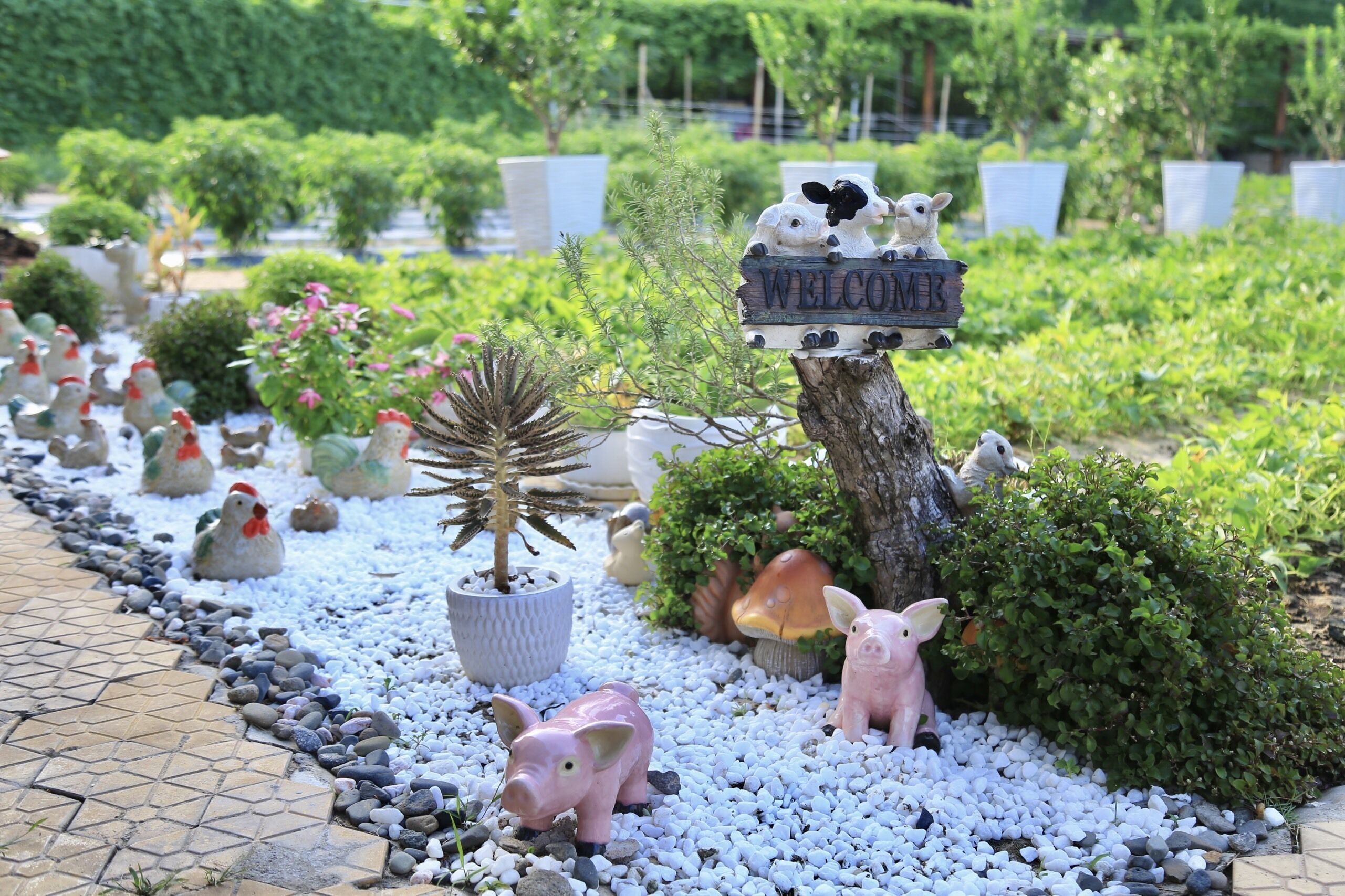 A garden pathway lined with decorative animal figurines and a welcome sign.