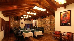 Un espace repas avec des tables et des chaises en bois, des murs en pierre et un plafond rustique.
