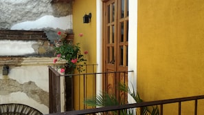 A yellow building with a wooden door and a balcony with a metal railing. - Hotel Candelaria Antigua (Antigua Guatemala)