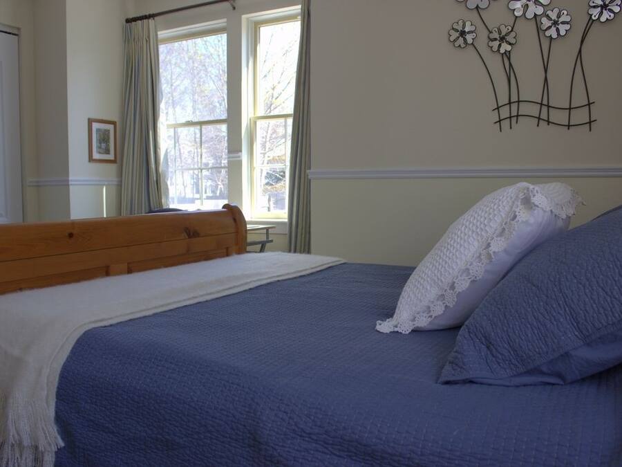 A bedroom with a wooden headboard, a blue bedspread, and a white blanket.