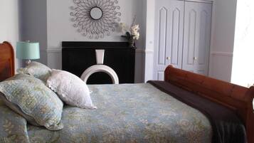 Un dormitorio con cama, mesita de noche, cómoda y espejo instalado en la pared.