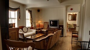 A traditional living room with a sofa, armchairs, a television, and a fireplace.
