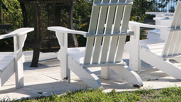 A gazebo and Adirondack chairs overlooking a lake with forested hills in the background.