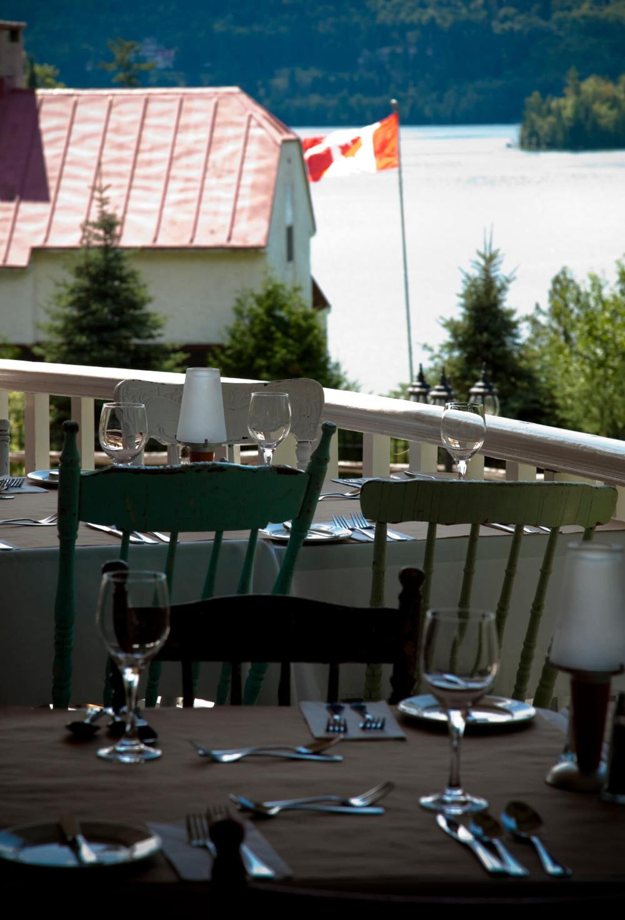Une table à manger avec des chaises, un drapeau, et en arrière-plan, une vue sur un lac et un bâtiment.