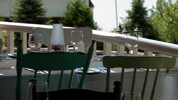 Une table à manger avec des chaises, un drapeau, et en arrière-plan, une vue sur un lac et un bâtiment.
