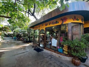 A storefront with a curved facade, large glass windows, and a variety of plants both inside and outside.