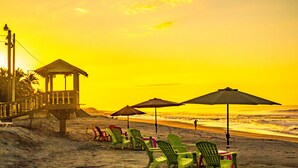 Une plage avec un poste de surveillance pour les sauveteurs, des chaises longues et des parasols.