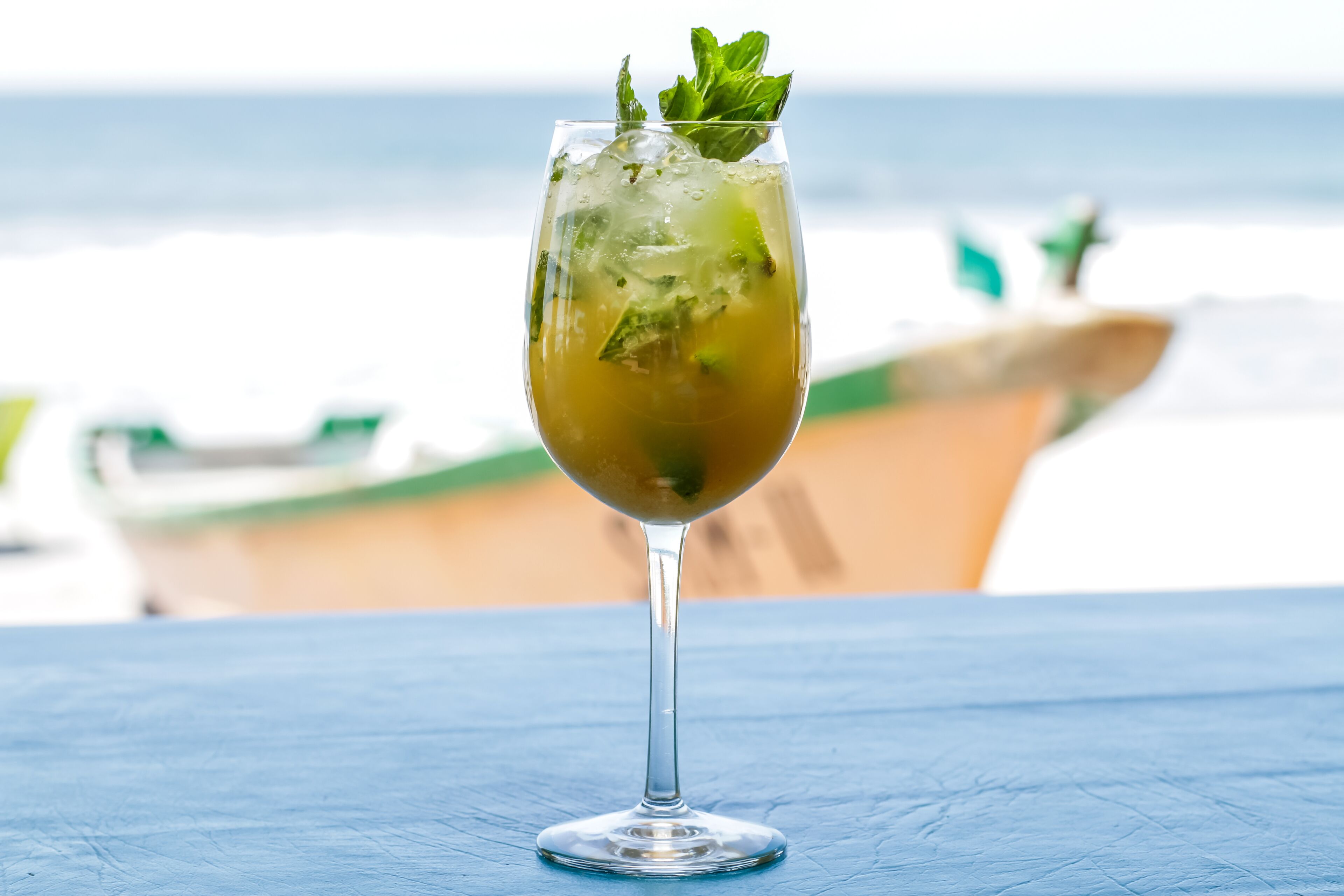 Een glas drinken op een tafel met uitzicht op de oceaan en een boot op de achtergrond.