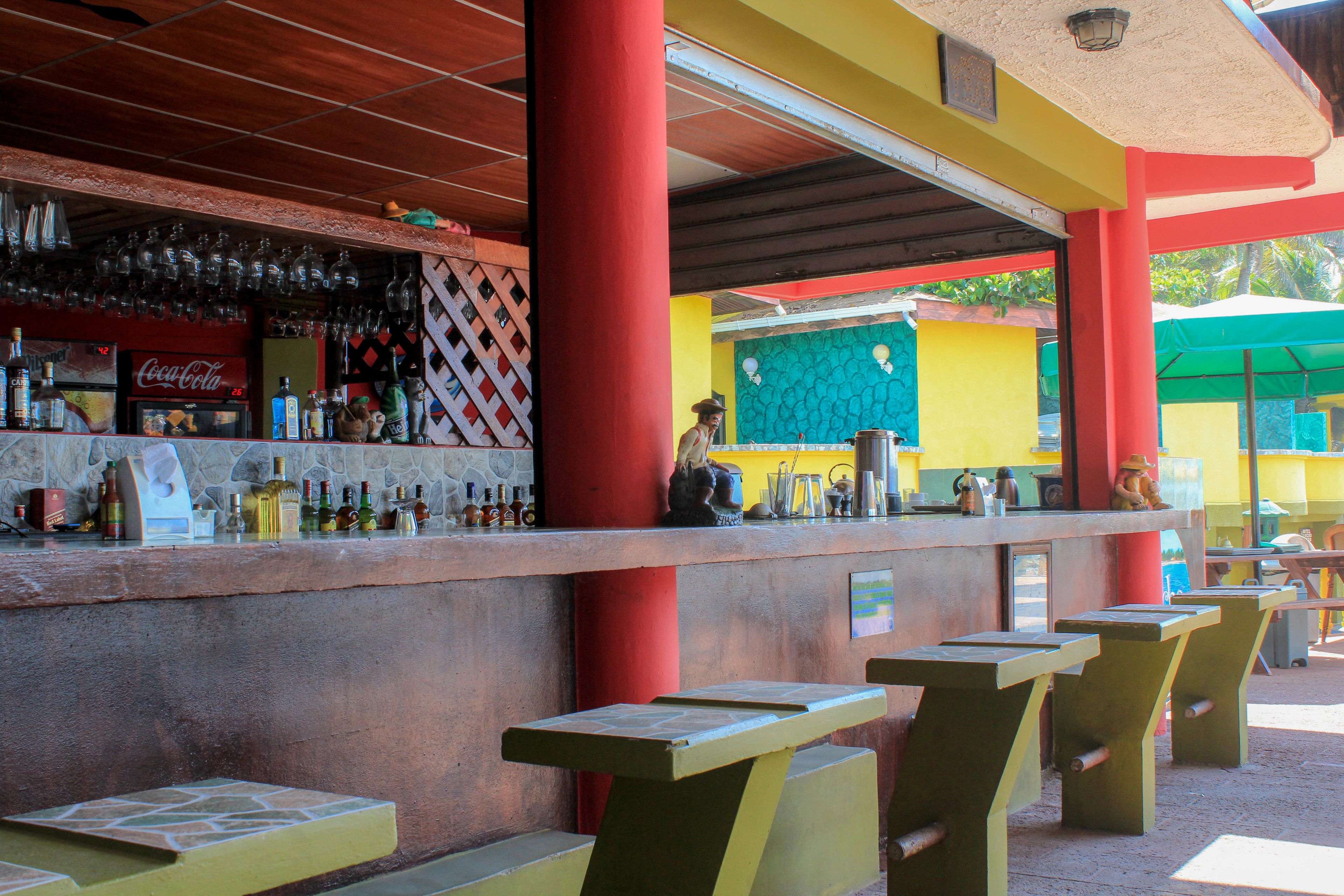 Zona de bar con mostrador, asientos y refrigerador de Coca-Cola.