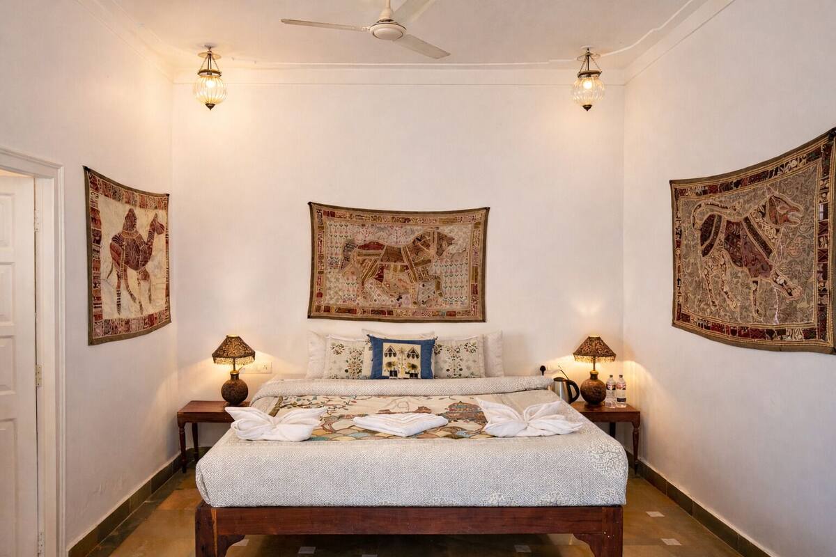 Une chambre à coucher comprenant un lit, deux tables de chevet, un ventilateur de plafond et trois lampes fixées au mur.